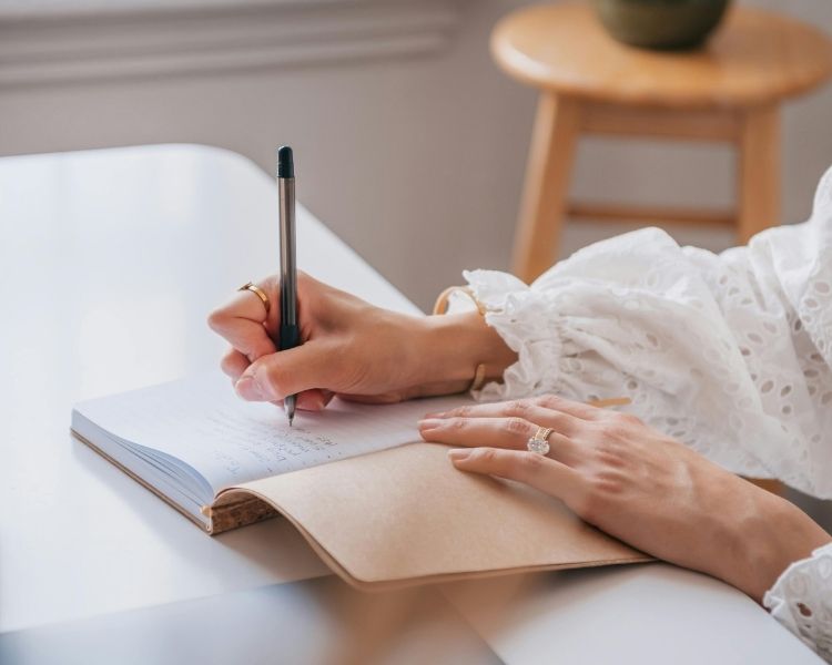 Services relecture freelance Personne écrivant dans un carnet.